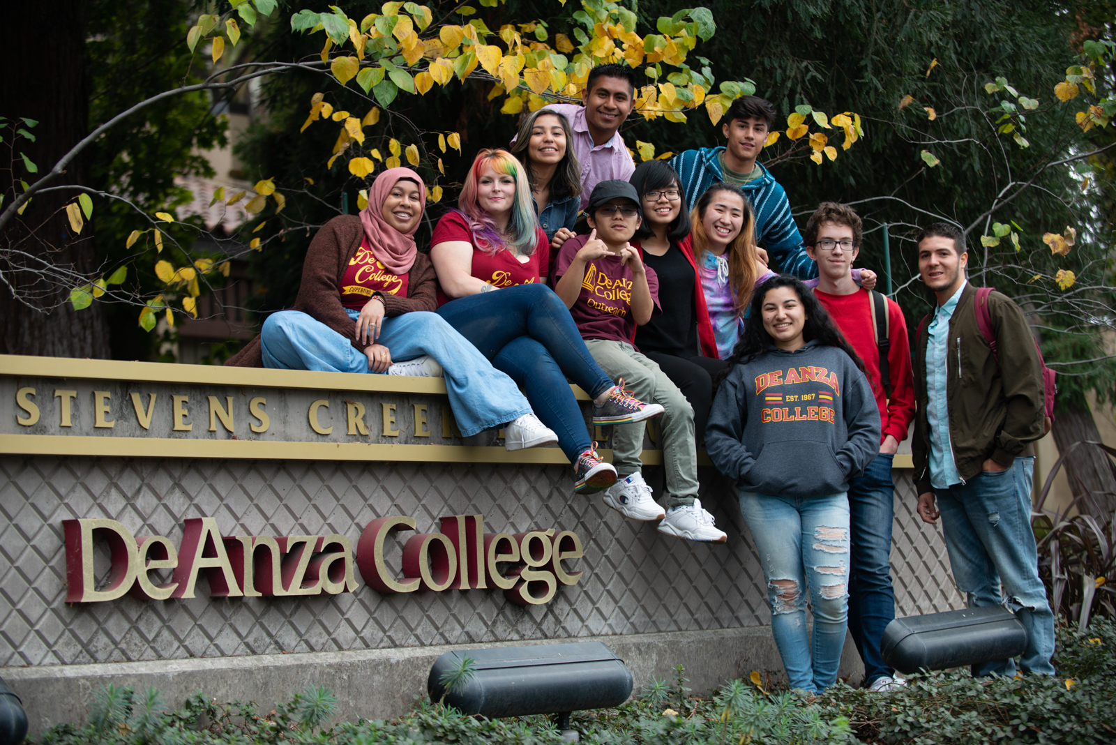 students sitting on wall with De Anza sign